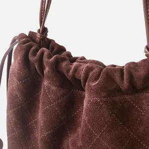 Détail de sac seau matelassé en suédine marron, texture de luxe sac à bandoulière élégant.