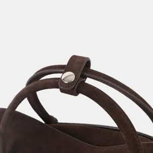 Détail de la poignée de sac fourre-tout en cuir suédé marron avec bouton-pression métal.