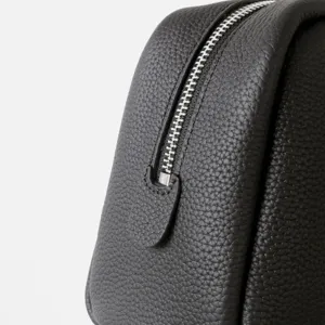 Gros plan sur la fermeture eclair du sac en cuir noir, texture en cuir de vache de qualite.