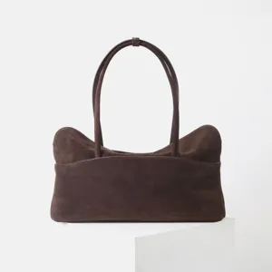 Gros plan détaillé du sac cabas en daim marron foncé, mettant en valeur sa texture élégante.