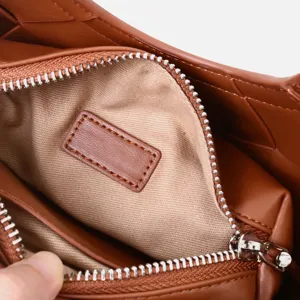 Brown woven leather handbag interior detail, zipper pocket and lining close-up view.