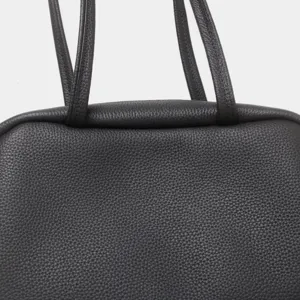 Gros plan detail du sac a main en cuir veritable noir avec texture fine et doubles poignees.
