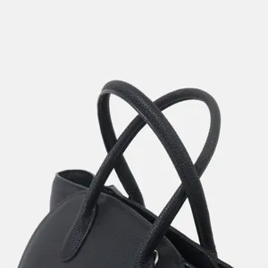 Gros plan sur les poignées texturées et les coutures fines de ce sac fourre-tout noir.