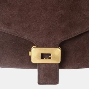 Gros plan sur un sac à main en cuir suédé marron avec fermoir métallique doré poli.