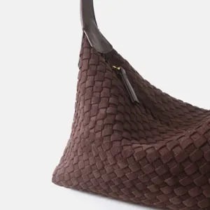 Gros plan de la texture en cuir tressé marron foncé, montrant l'artisanat et le sac hobo souple.