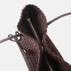 Gros plan détail d'un sac à main marron en cuir tressé avec fermeture zippée de luxe.