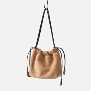 Gros plan sur le sac seau matelassé en suède marron avec texture de coutures losanges.