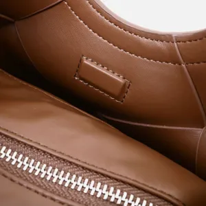 Close-up detail of brown leather handbag interior showcasing premium texture and smooth metal zipper.