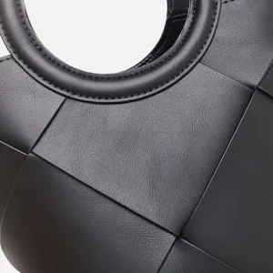 Detailed close-up of luxury black woven leather handbag showing fine texture and geometric design.