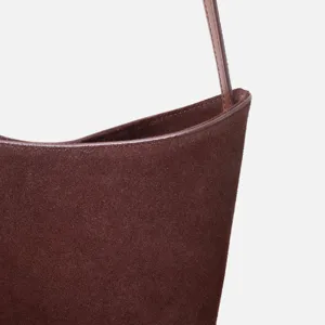 Détail de sac sous les bras en daim marron, texture douce de qualité, design épuré.