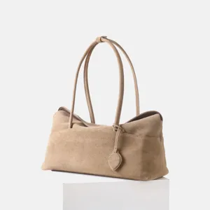 Détail de sac à main en daim kaki, design rétro minimaliste avec double anse et pendentif.
