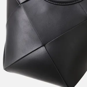 Close-up detail of black leather woven handbag, modern geometric texture and premium finish.