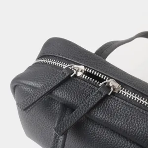 Vue rapprochée de la fermeture éclair et des détails en cuir grainé du sac pour femme.