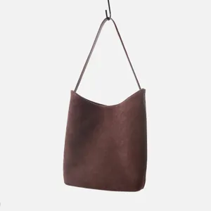 Détail de sac porté épaule en daim marron, élégant sac à main minimaliste pour le quotidien.