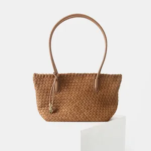 Vue détaillée du sac à main en cuir tressé marron avec savoir-faire et nœud en métal.