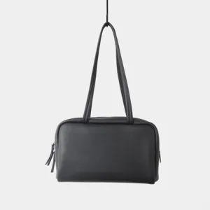 Sac porté épaule en cuir grainé noir, détail de sac boston minimaliste zippé, chic et urbain.