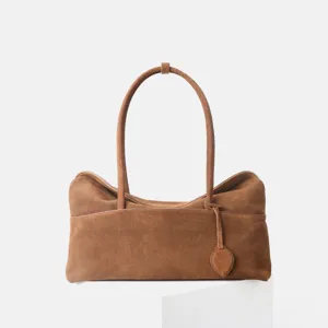 Vue detaillee du sac a main en daim marron avec texture douce et poignees fines.