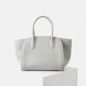 Vue détaillée du sac cabas minimaliste en cuir gris clair avec texture fine et lignes épurées.