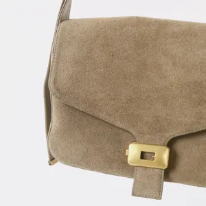 Gros plan sur le sac bandoulière en daim avec élégant fermoir métallique. Accessoire chic.