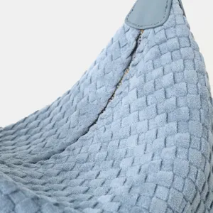 Gros plan sur le détail en cuir tissé bleu clair du sac porté épaule hobo, texture douce.