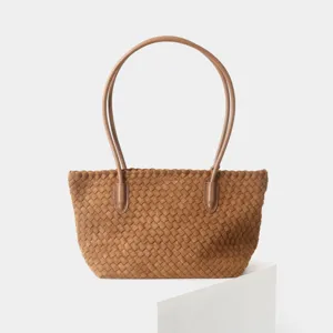 Gros plan sur la texture en cuir tissé et les détails des anses du sac fourre-tout.