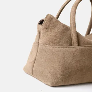 Gros plan détaillé du sac à main en daim kaki montrant sa texture raffinée et ses belles finitions.