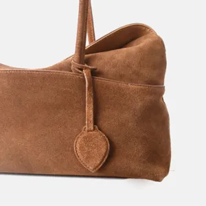 Vue détaillée d'un sac cabas marron en daim pour femme, sac porté épaule vintage avec pendentif.