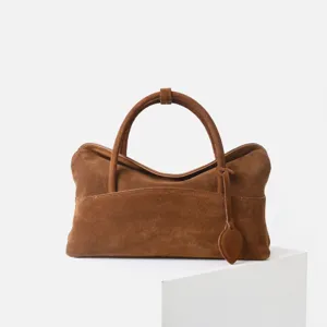 Vue détail du sac cabas en daim marron montrant le cuir souple et la poignée.
