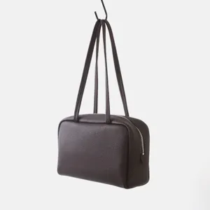Vue détaillée du sac Boston en cuir marron suspendu, texture pebble et fermeture éclair.