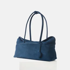 Détail du sac porté épaule en daim bleu foncé, design rétro élégant, texture fine et douce.