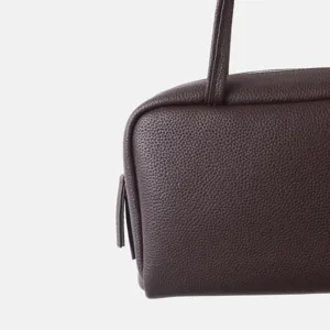 Vue détaillée de la texture de surface en cuir de vachette grainé marron foncé du sac.