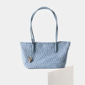 Gros plan montrant les détails et le savoir-faire du sac cabas épaule en cuir tissé bleu clair