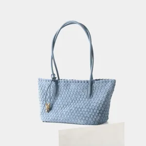 Détail de sac à main en cuir tissé bleu clair avec texture tressée fine et nœud en métal.
