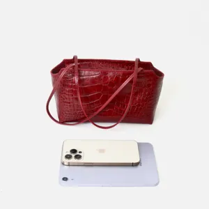 Red crocodile pattern leather underarm bag detail view showing spacious capacity with devices.