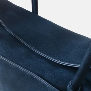 Gros plan détaillé du sac bandoulière en suède bleu marine avec une belle texture.