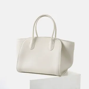 Gros plan détaillé du sac cabas minimaliste en cuir blanc montrant sa texture et ses soufflets.