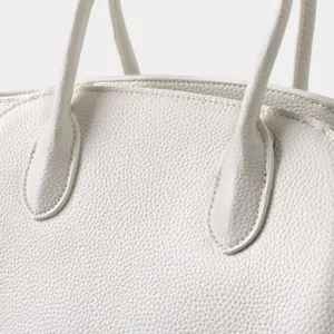 Gros plan detaille d un sac a main en cuir grene blanc, montrant une finition de qualite.