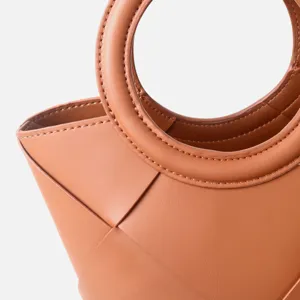 Elegant brown leather handbag with circular handle and chic geometric woven design for women.