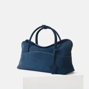 Vue détaillée du sac à main en daim bleu foncé, montrant une texture douce et de belles poignées.