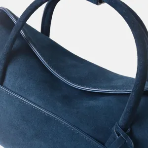 Gros plan d'un sac à main en cuir suédé bleu foncé, montrant de superbes coutures.