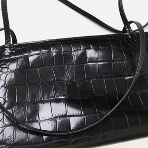 Detailed close-up view of black crocodile embossed leather shoulder bag surface texture.