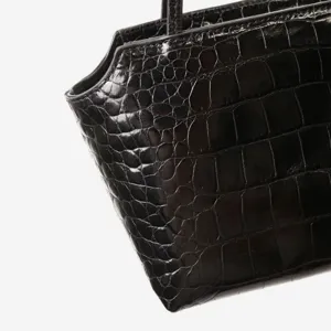 Black crocodile embossed leather top handle bag detail shot, premium commuting handbag.