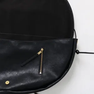 Gros plan du sac bandoulière demi-lune en cuir noir, détail minimaliste du sac besace.