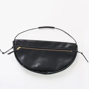 Vue détaillée du sac porté épaule demi-lune en cuir noir, montrant la texture et la fermeture.