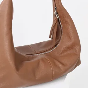 Gros plan sur le sac souple en cuir marron avec coutures fines et fermeture éclair.
