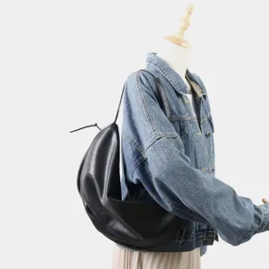 Gros plan détail du sac porté épaule demi-lune noir slouchy, design minimaliste et tendance.
