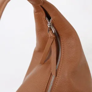 Détail de sac porté épaule hobo en cuir souple marron, gros plan sac besace fourre-tout chic.