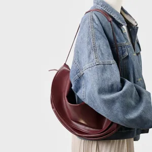 Vue detaillee du sac porte epaule en cuir croissant bordeaux montrant une texture elegante.