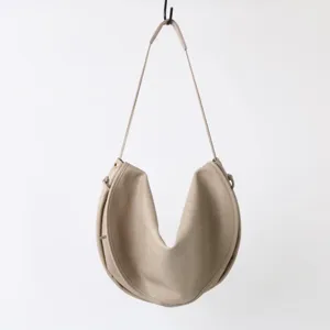 Gros plan sur le detail du sac porte-epaule croissant minimaliste au design en U unique.