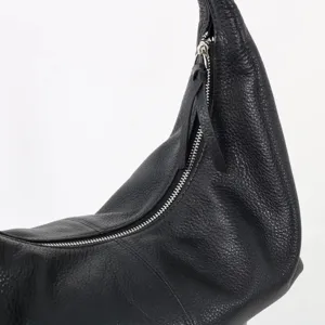 Vue détaillée de la fermeture éclair du sac à bandoulière en cuir souple noir et de sa forme.